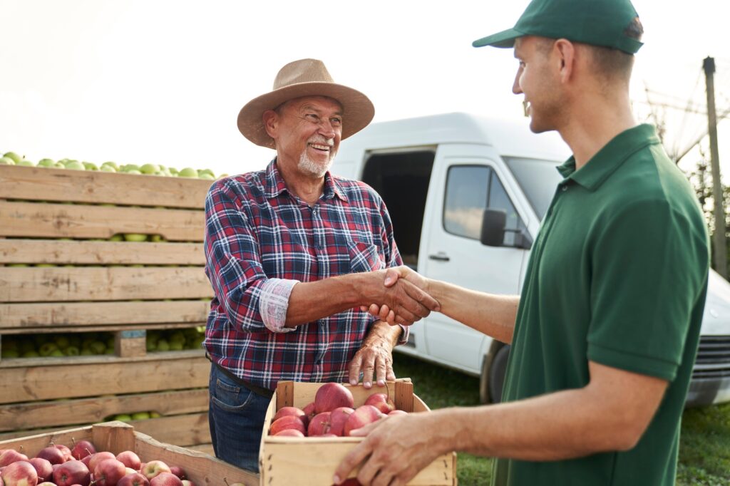 Handshake of orchard senior farmer and sales representative